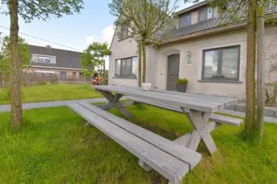 a wooden bench sitting in the grass in front of a house at Saffels Nest in Lochristi