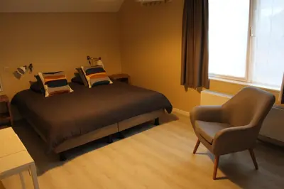a bedroom with a bed and a chair and a window at Saffels Nest in Lochristi