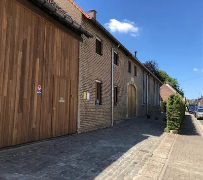 a brick building with a wooden door on a street at Constantinus in Herzele