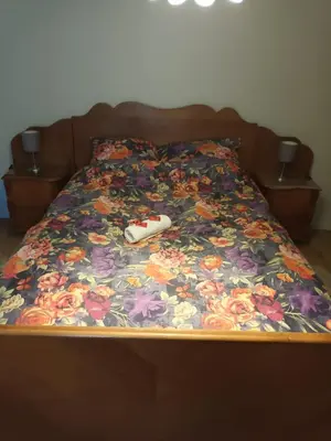 a bed with a flower blanket with a remote control on it at The best known village of Belgium in Puurs