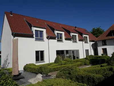 a white house with red roofs and a cat in front of it at B&B Dotter 17 in Erpe-Mere
