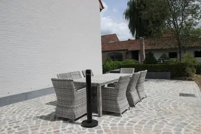 a table with wicker chairs on a patio at B&B Dotter 17 in Erpe-Mere