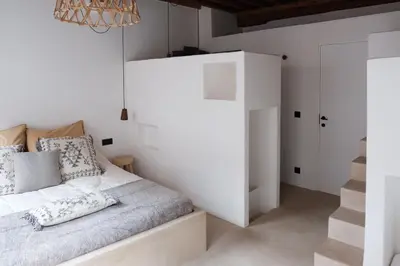 a white bedroom with a bed and a staircase at Boutique Holiday Home ZaligInAntwerpen 77 in Antwerp