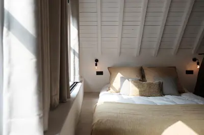 a bedroom with a bed with white walls and a window at Boutique Holiday Home ZaligInAntwerpen 77 in Antwerp