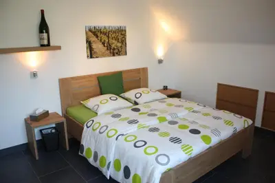a bedroom with a large bed and a bottle of wine at Hotel Gasthof Kapelhof in Erpe-Mere
