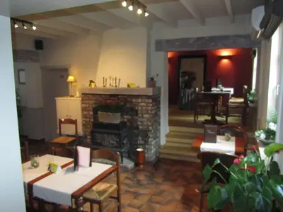a living room with a fireplace and tables and chairs at Hotel Klein Nederlo in Vlezenbeek
