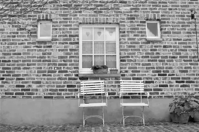 two chairs sitting in front of a brick building at De Volle Maan in Sint-Lievens-Houtem