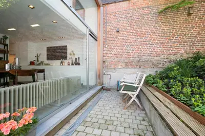 a patio with a bench and a brick wall at 1bd apartment with garden Brugmann area in Brussels