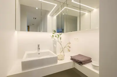 a white bathroom with a sink and a mirror at 1bd apartment with garden Brugmann area in Brussels