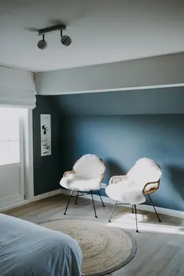 two white chairs in a bedroom with a blue wall at Charmeverblijf Juliette in Kasterlee