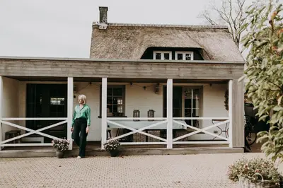 a woman standing in front of a house at Charmeverblijf Juliette in Kasterlee
