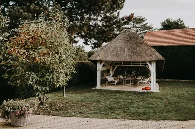 a gazebo with a table and chairs in a yard at Charmeverblijf Juliette in Kasterlee