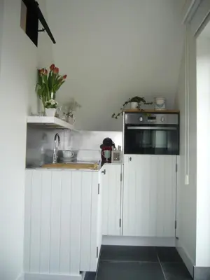 a kitchen with white cabinets and a sink at De Moeraseik in Zele