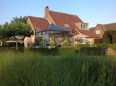 a house with a conservatory in the middle of a yard at De Moeraseik in Zele