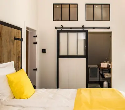 a bedroom with a door and a yellow pillow on a bed at De Moeraseik in Zele