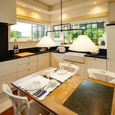 a kitchen with a wooden table and two lights at De Moeraseik in Zele