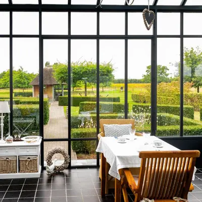 a dining room with a table and views of a garden at De Moeraseik in Zele