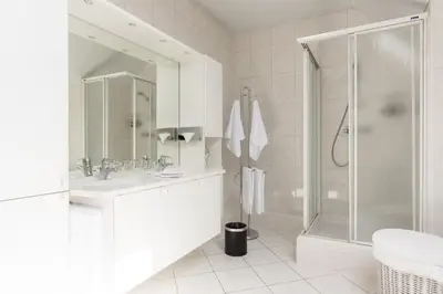 a white bathroom with a shower and a sink at Lovely Guesthouse Lier in Lint