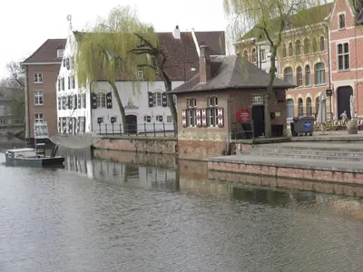a river with buildings and a boat in the water at Lovely Guesthouse Lier in Lint