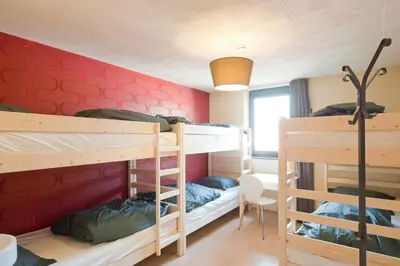 a room with two bunk beds and a red wall at Leuven City Hostel in Leuven