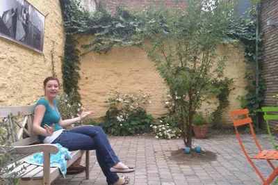a woman sitting on a bench in a garden at Leuven City Hostel in Leuven