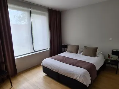a bedroom with a large bed and a large window at B&B A Côté du Cinquantenaire in Brussels