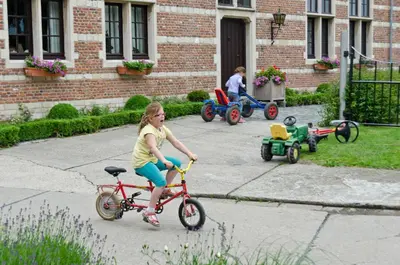 a young girl riding a bike in a yard with toy cars at B&B Euverbraeke in Beveren