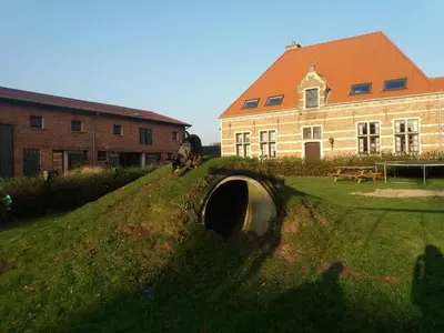 a building with a tunnel in the grass next to a building at B&B Euverbraeke in Beveren