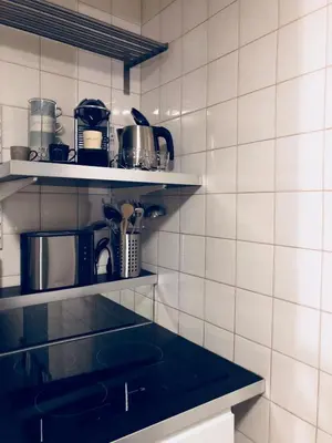a kitchen with white tiled walls and shelves at Olives in Brussels