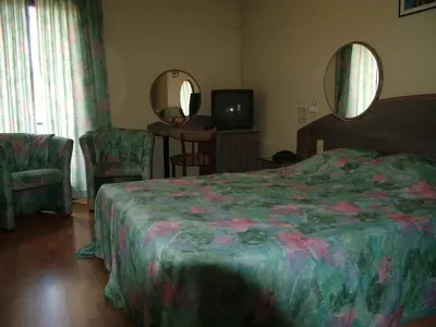 a bedroom with a bed and two chairs and a mirror at Alsput Hotel in Halle
