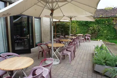 a group of tables and chairs with an umbrella at Alsput Hotel in Halle