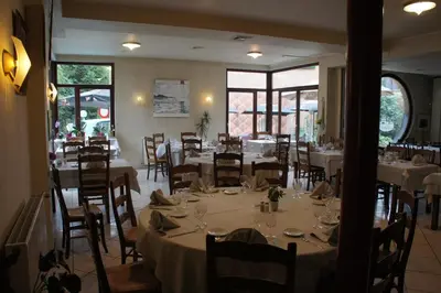 a dining room with white tables and chairs and windows at Alsput Hotel in Halle