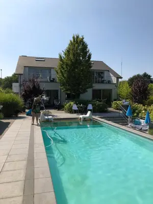 a woman is standing next to a swimming pool at Guesthouse De Witte Merel Deluxe in Tessenderlo