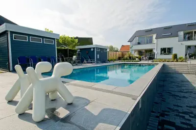 a swimming pool with white sculptures in front of a house at Guesthouse De Witte Merel Deluxe in Tessenderlo