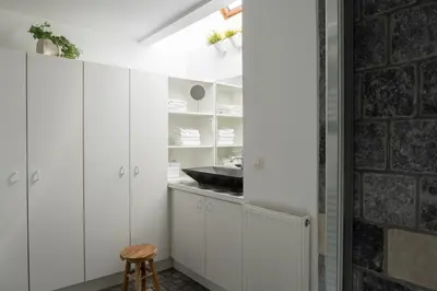 a kitchen with white cabinets and a brick wall at B&B De Joker in Turnhout