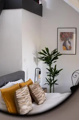 a room with a bed with yellow pillows and a plant at B&B De Joker in Turnhout