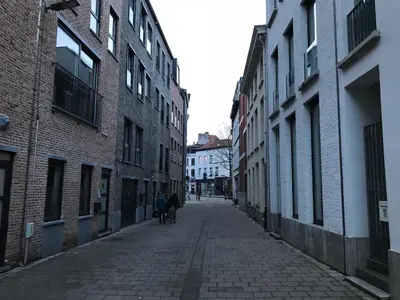 an alley with two people and a dog walking down a street at Modern cozy studio with backyard in Antwerp