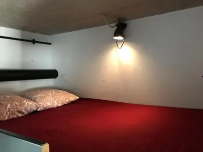 a bedroom with a red bed with a light on the wall at Modern cozy studio with backyard in Antwerp