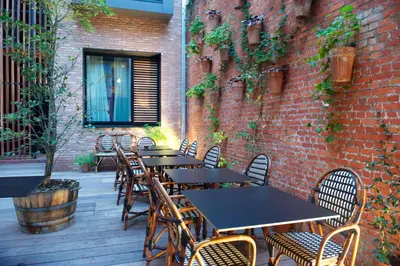 a patio with tables and chairs and a brick wall at Latroupe Hotel Le Berger in Brussels