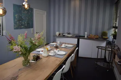 a dining room table with a vase of flowers on it at De Pauw B&B in Zele