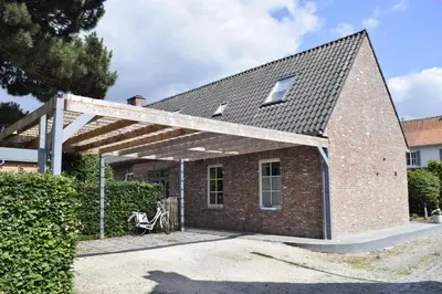 a brick house with a wooden pergola at De Pauw B&B in Zele