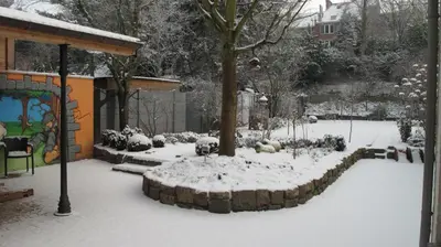 a garden covered in snow with a tree in it at Hotel Guesthouse Begijnhof in Leuven