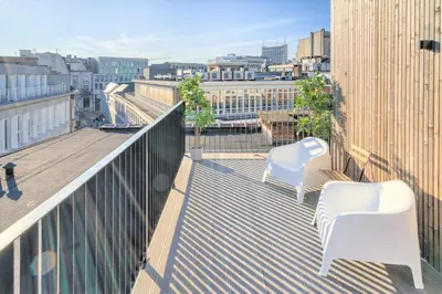 a balcony with two white chairs and a view of a city at The Meir Lodge. Apartments in heart of Antwerp in Antwerp