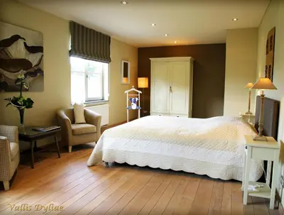 a bedroom with a large white bed and a chair at B&B Vallis Dyliae in Korbeek-Dijle
