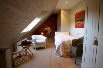 a bedroom with a bed and a chair in a attic at B&B Vallis Dyliae in Korbeek-Dijle