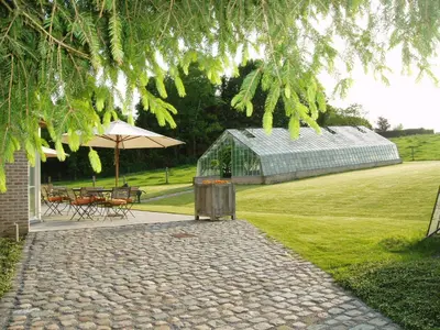 a garden with a greenhouse and a table and chairs at B&B Vallis Dyliae in Korbeek-Dijle
