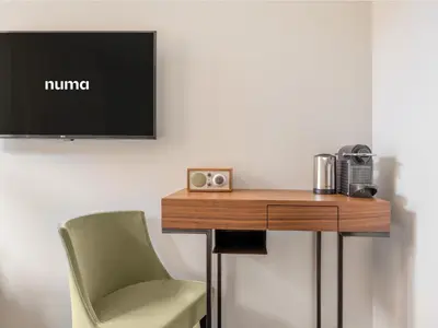 a desk with a chair and a television on a wall at Numa Brussels Lief in Brussels