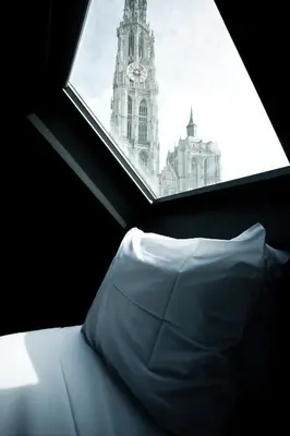a window with a white pillow and a clock tower at HotelO Kathedral in Antwerp