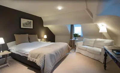 a bedroom with a large bed and a white couch at Hotel Hippocampus in Mol