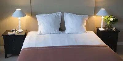 a bedroom with a bed with pillows and two lamps at Hotel Hippocampus in Mol